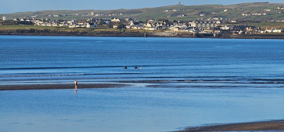 2 surfers in the middle of the beach waiting for a rideable wave